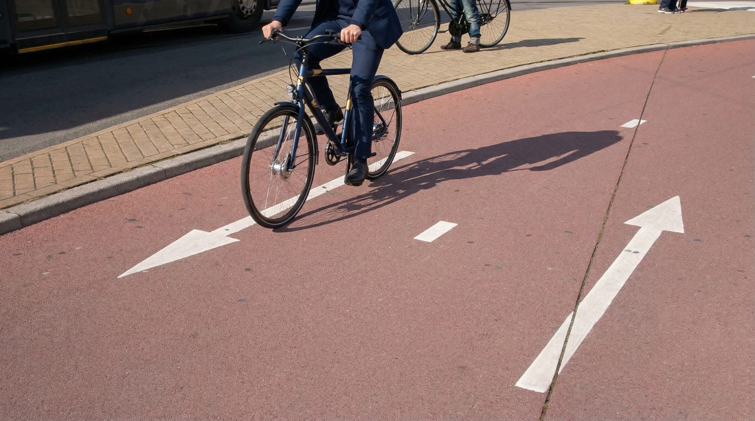 Fietser in pak op een rode fietsstrook met witte pijlmarkeringen